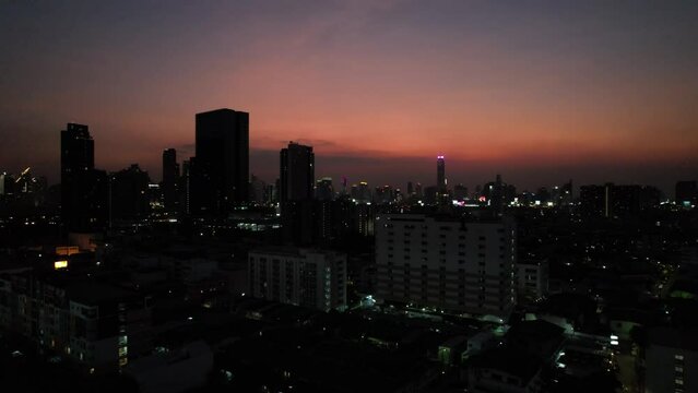  night illumination of Bangkok at sunset with orange sky and dark buildings