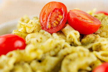 Pasta Creste Di Gallo with pesto sauce and cherry tomatoes, closeup. Rooster scallop.