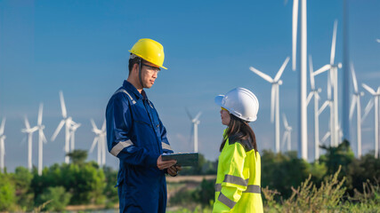 Two engineers working and holding the report at wind turbine farm Power Generator Station on...