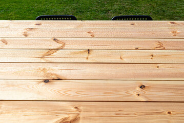 A modern table made of raw wood covered with yacht varnish, standing on the garden terrace.