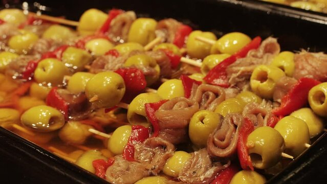 Marinated green olives in spicy sauce with fish and cheese tapas, spanish traditional food, ideal for Mediterranean dish or snack, market in barcelona.