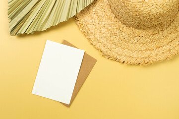 Top view of straw hat, dried palm leaf and card on yellow background. Summer fashion, vacation and...