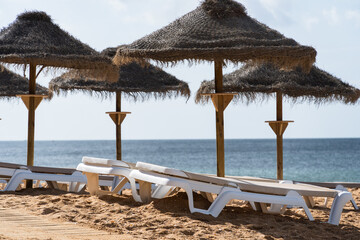 Straw chairs and umbrella. Praia do Peneco beach, Albufeira, Algarve, Portugal. Praia dos Pescadores beach. Fishermen, sunny day