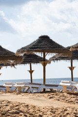 Straw chairs and umbrella. Praia do Peneco beach, Albufeira, Algarve, Portugal. Praia dos Pescadores beach. Fishermen, sunny day