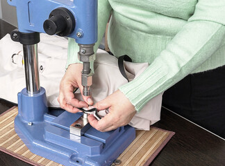 in a sewing workshop close-up of female hands and a riveting machine on fabric.
