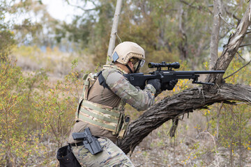 Fototapeta premium Soldier airsoft player dressed in camouflage uniform wielding a sniper rifle