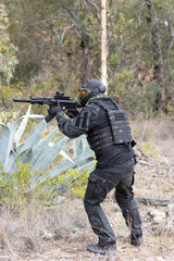 Soldier airsoft player dressed in black uniform wielding a black assault rifle