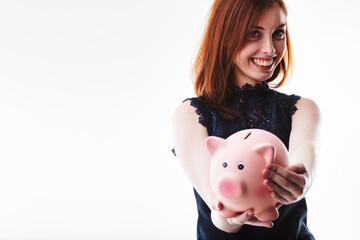 Auburn-haired woman holds piggy bank, smiling brightly
