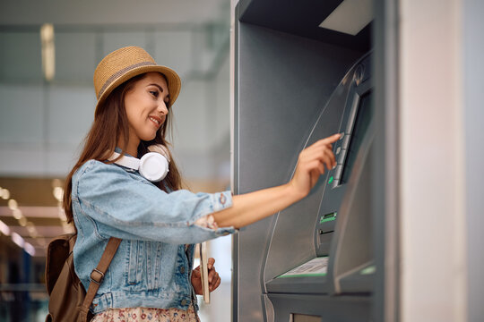 Young woman using ATM at airport.