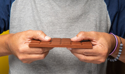 hands of an unrecognizable man breaking a chocolate bar