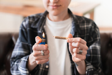 Close up image of weed joint and hipster lighting it up. Legalization of marijuana and cannabis...