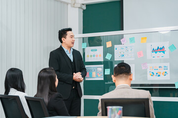 Asian businessman present start up project to expert investor, Teamwork group of multicultural business team solving problems, discussing business idea with skyscraper at modern business lounge