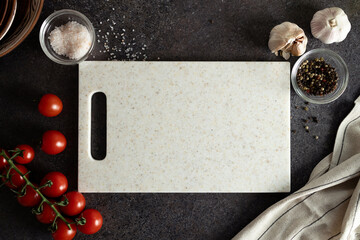 Ingredients for cooking - cherry tomatoes, garlic, salt, black pepper, empty cutting board and...