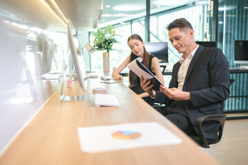 Asian businessman present start up project to expert investor, Teamwork group of multicultural business team solving problems, discussing business idea with skyscraper at modern business lounge