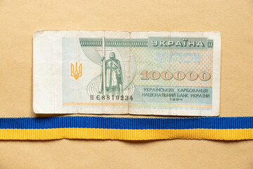 One hundred thousand Ukrainian Carbonates and a ribbon of the Ukrainian flag blue on brown paper,...