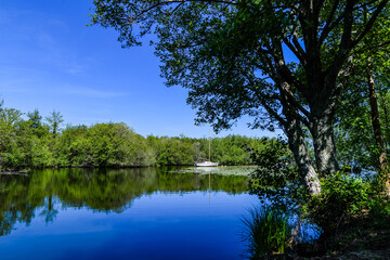 Beautiful landscape of Lake Soustons in southwest France with a small sailboat in a cove.