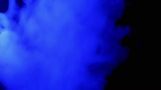 Explosion of Blue Smoke or Vapor on Black Blurred Background. Abstract. Top view. Flash. Passing smoke. Soft puffs of smoke or steam mix chaotically on empty space. Particle explosion, bright light.