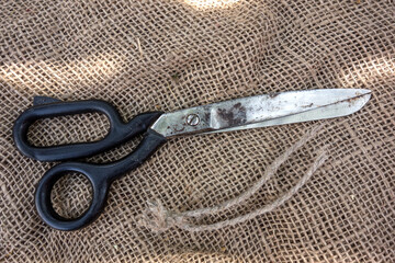 Large vintage sartorial scissors on a background of rough burlap