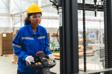 African American female worker driving forklift truck in heavy metal industrial factory, Smiling...