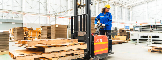 African American female worker driving forklift truck in heavy metal industrial factory, Smiling...