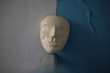 an abstraction with a theatrical mask against an old wall