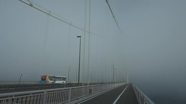 A bus travelling over the bridge covered in thick fog. Forth Road Bridge, Scotland, United Kingdom