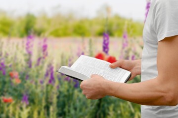 Open bible in human hands outdoor