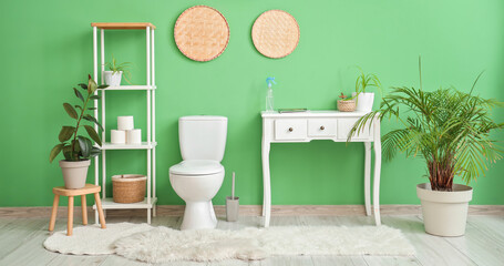 Interior of restroom with toilet bowl near green wall