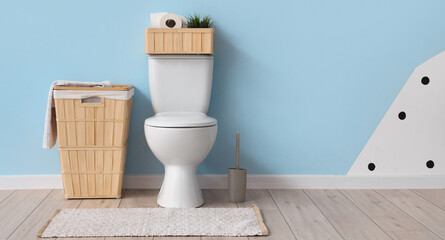 Interior of restroom with toilet bowl and baskets near blue wall. Banner for design