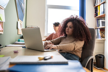 The female student, huddled over textbooks and notes, diligently prepare for an upcoming exam.	
