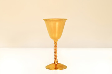 Golden antique goblet with high stem on the white table. Close-up. Copy space.


