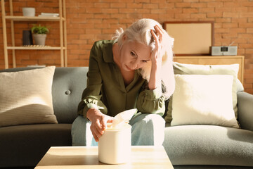 Depressed mature woman sitting on sofa at home