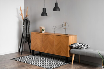 Wooden cabinet with bench and carpet near grey wall