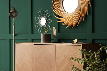 Wooden cabinet with lamp and mirrors near green wall