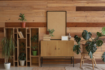Cabinet with flowerpots and frames near wooden wall