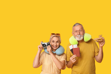 Mature couple with travel accessories on yellow background
