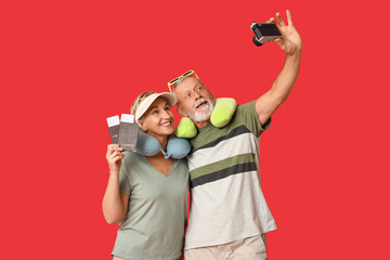 Mature couple with passports taking selfie on red background. Travel concept
