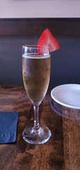 tall thin glass of champagne with a slice of strawberry on a table in a restaurant, champagne,...