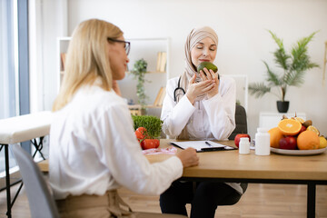 Arab female doctor makes treatment plan for gastrointestinal tract while sitting at table in modern...