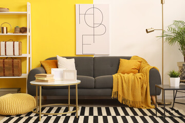 Interior of stylish living room with sofa, poster and blank frames on table