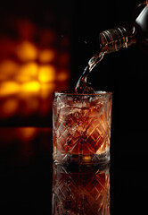 Pouring whiskey into a glass with ice.