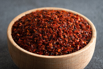 Red pepper flakes.Red chili peppers in wooden bowl on black background
