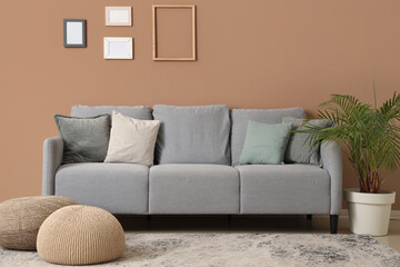 Interior of living room with sofa, poufs and blank photo frames