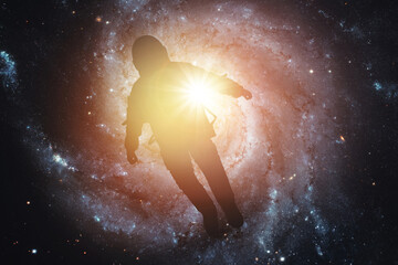 Silhouette of an astronaut in space against the background of the galaxy. Elements of this image furnished by NASA