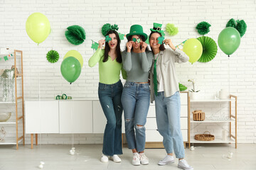 Naklejka premium Beautiful young women with clover at home. St. Patrick's Day celebration