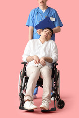Young man in wheelchair with doctor on pink background. National Cerebral Palsy Awareness Month