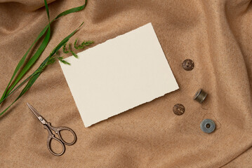 Empty white paper list with scissors and buttons on a fabric background from above. Copy space