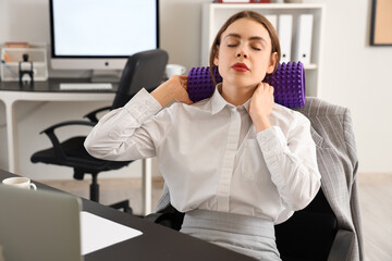 Young businesswoman with foam roller suffering from neck pain in office
