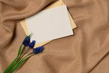 Empty white paper list with flower on a fabric background from above. Copy space