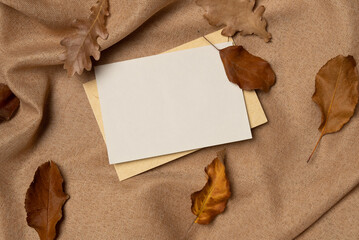 Empty white paper list with foliage on a fabric background from above. Autumn concept. Copy space
